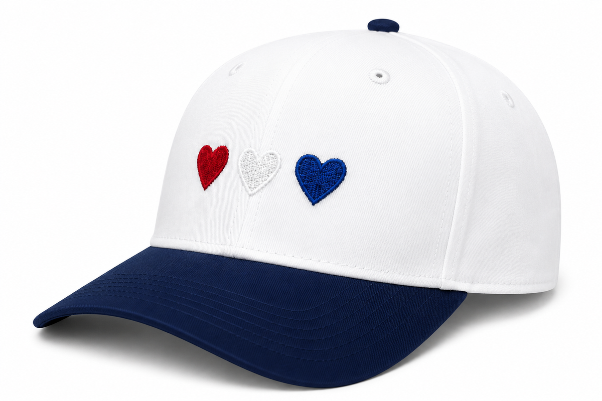 Side view of Red White & Blue Hearts Baseball Cap showing white structured crown, navy brim, and solid back with embroidered red, white, and blue hearts, on a white background.

