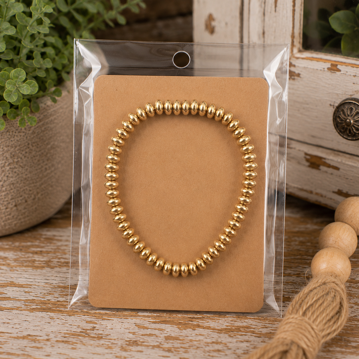 Gold beaded stretch bracelet stacked with two neutral beaded bracelets on wrist with cream sweater
