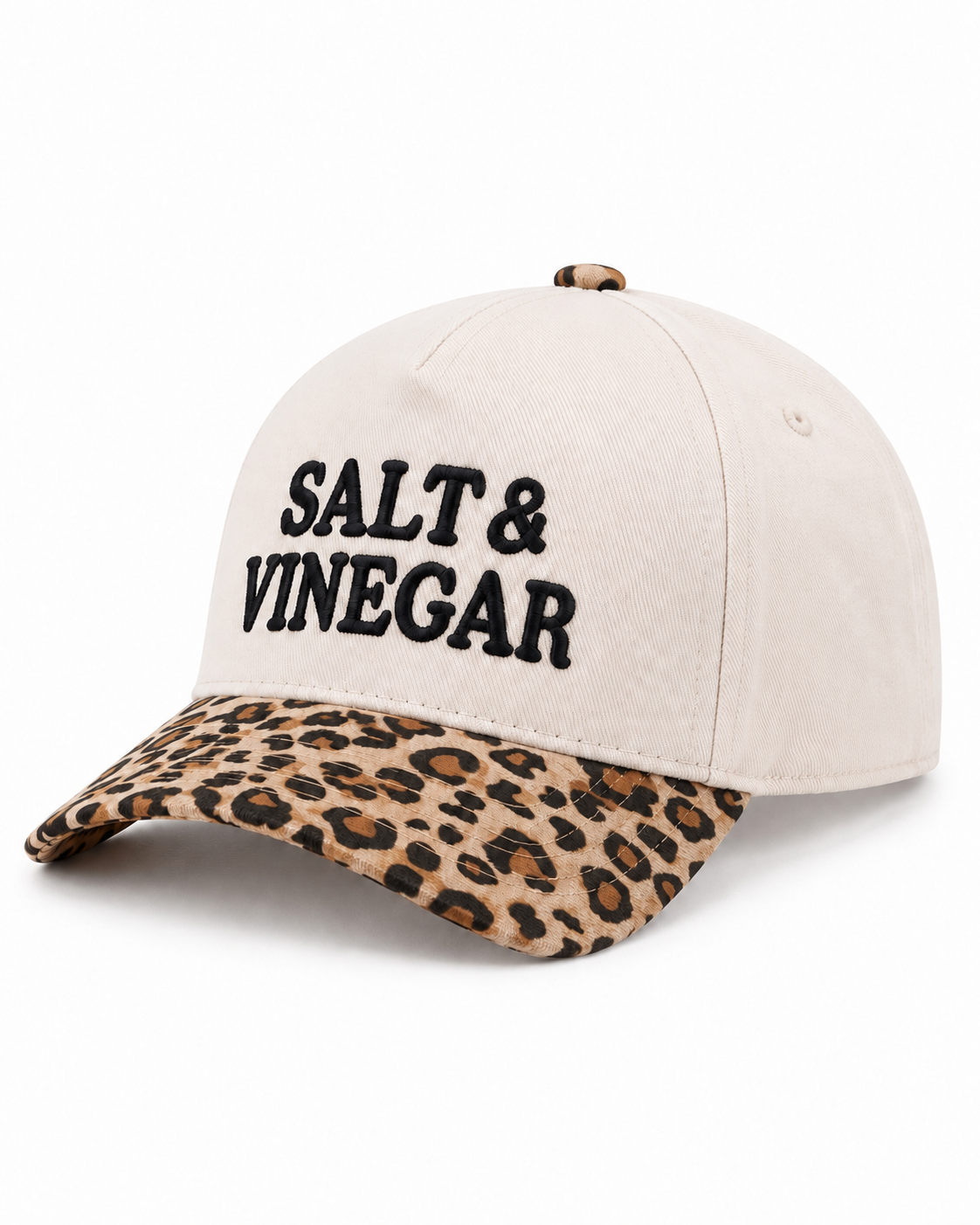Salt & Vinegar Two-Tone Baseball Cap in Leopard three-quarter angle view showing structured cream cotton crown with bold black embroidered Salt & Vinegar lettering, single ventilation eyelet on side panel, tan and brown leopard print bill, and leopard print top button on white background
