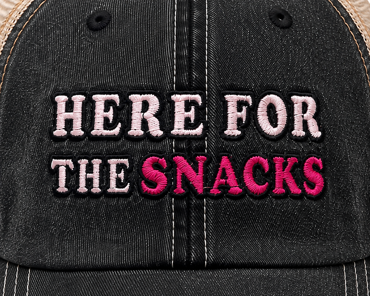 Close-up of Here for the Snacks embroidery in light pink and hot pink on distressed black trucker hat
