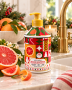 Molto Bella Sicilian Grapefruit hand soap beside a sink with sliced grapefruit, citrus fruit, Christmas greenery, and gold fixtures
