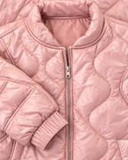 Close-up of the blush pink jacket showing its stand-up collar, silver-tone zipper, curved quilting, and elastic cuff
