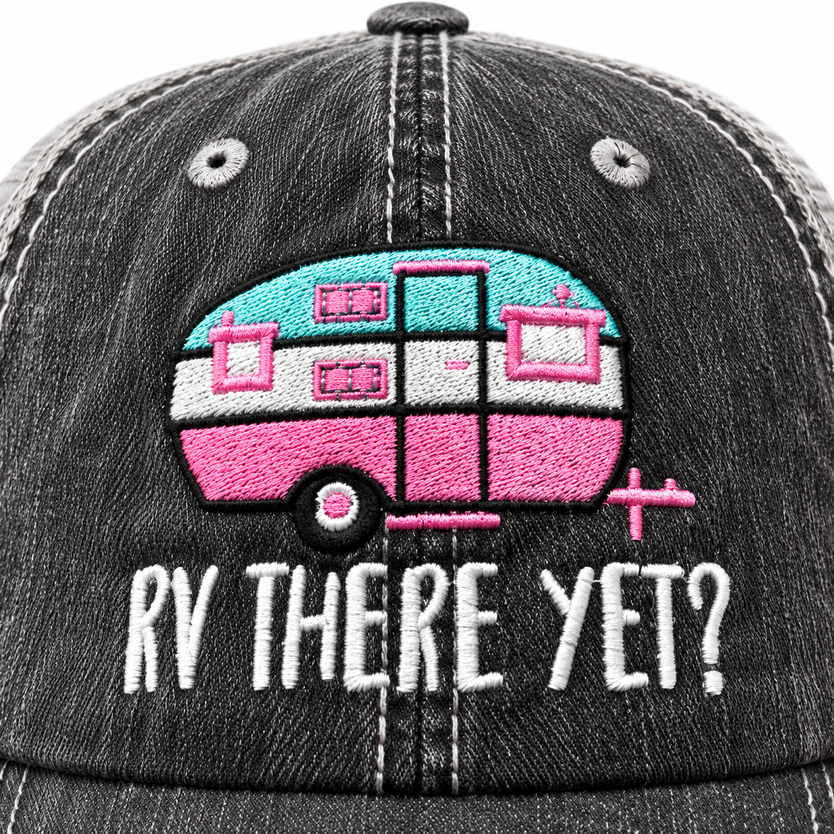 Close-up of embroidered aqua and pink retro camper graphic with white RV There Yet lettering on distressed black trucker hat front panel

