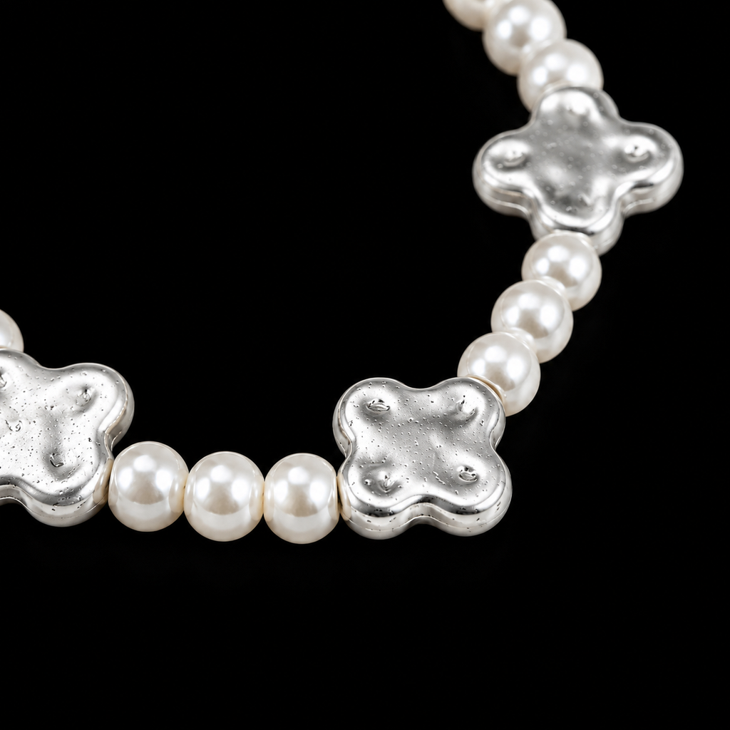 Close-up of creamy white pearl beads and hammered silver-tone clover accent beads on stretch bracelet
