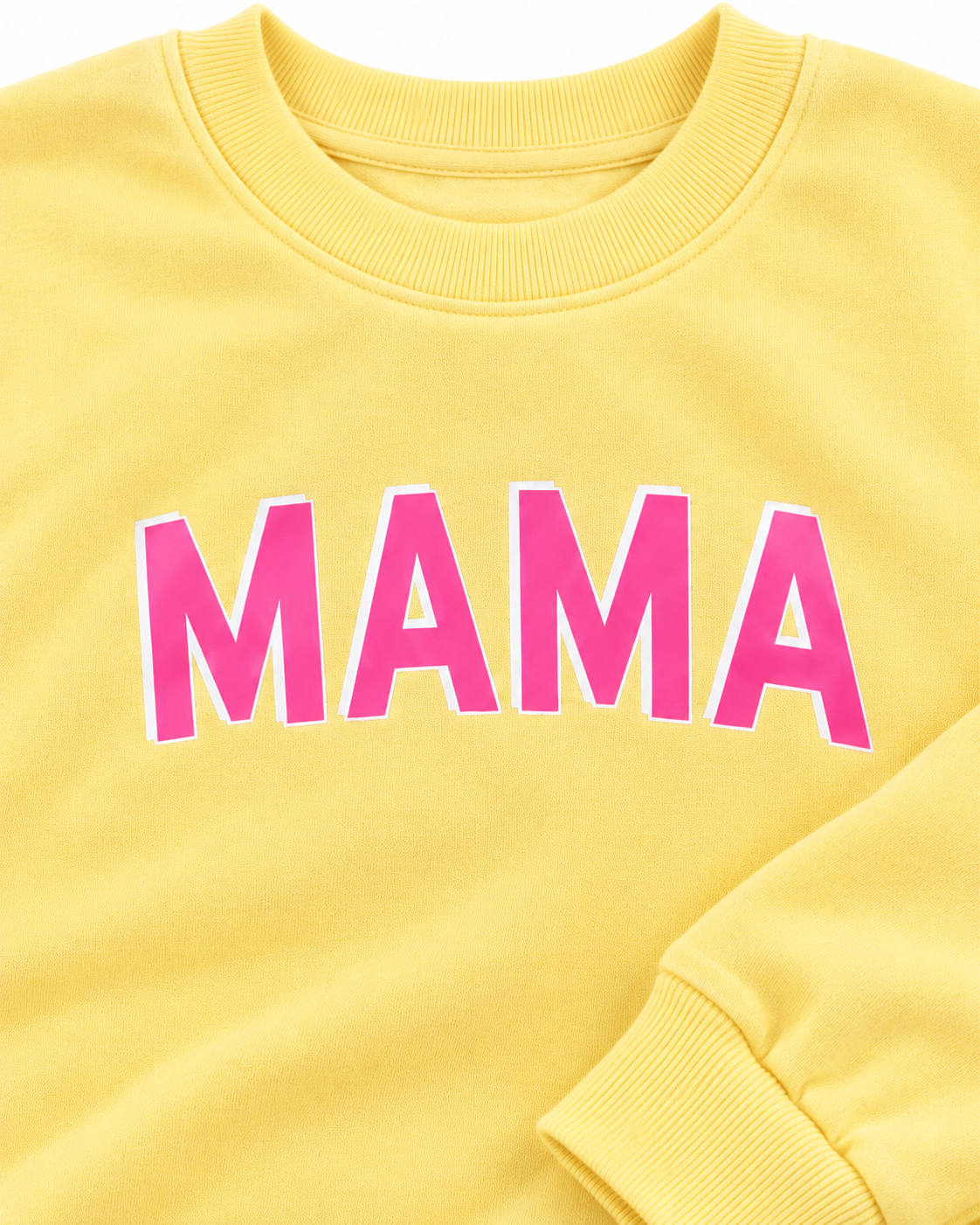 Close-up of pink MAMA lettering with a white outline on the yellow sweatshirt, showing the ribbed neckline and cuff
