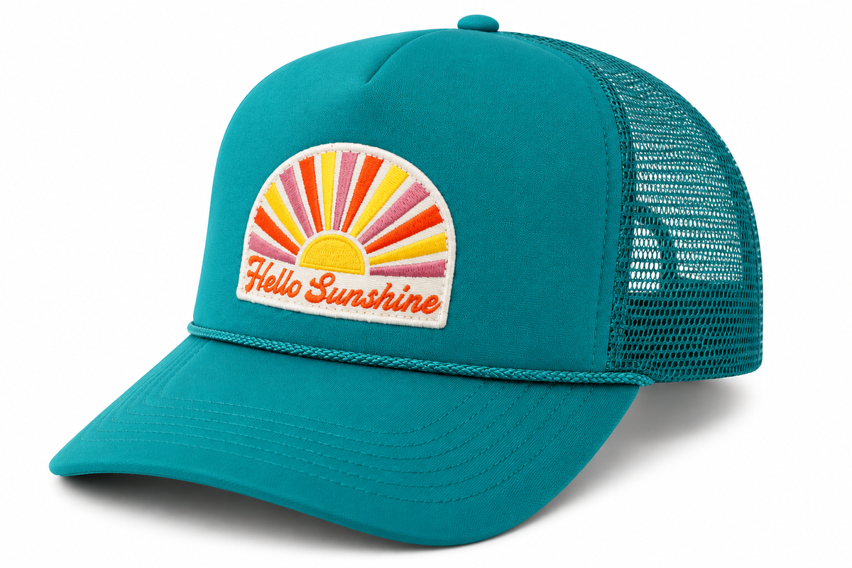 A teal trucker hat with a mesh back and a front patch that reads 'Hello Sunshine' with a retro sunburst design in yellow, orange, pink, and red, shown on a white background.