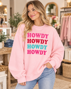 Model wearing the light pink Howdy crewneck sweatshirt with four colorful lettering rows, paired with jeans
