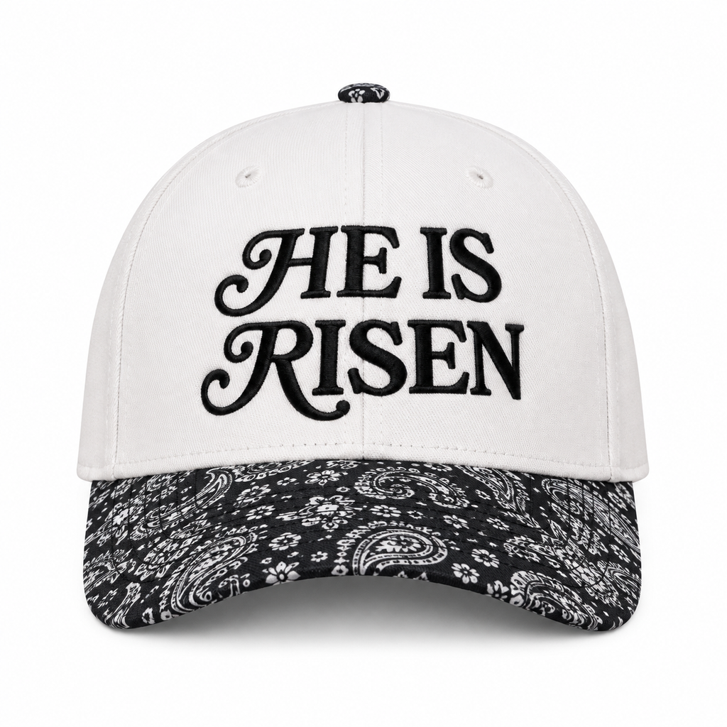 He Is Risen Baseball Cap in Black Paisley front view showing white cotton crown with black decorative script He Is Risen embroidery, black and white bandana paisley print bill, and paisley top button on white background
