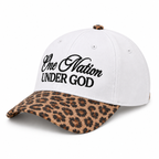 One Nation Under God Baseball Cap in Leopard three-quarter angle view showing white structured six-panel cotton crown with bold black embroidered script, white ventilation eyelets, leopard print top button, and tan and black leopard print bill on white background
