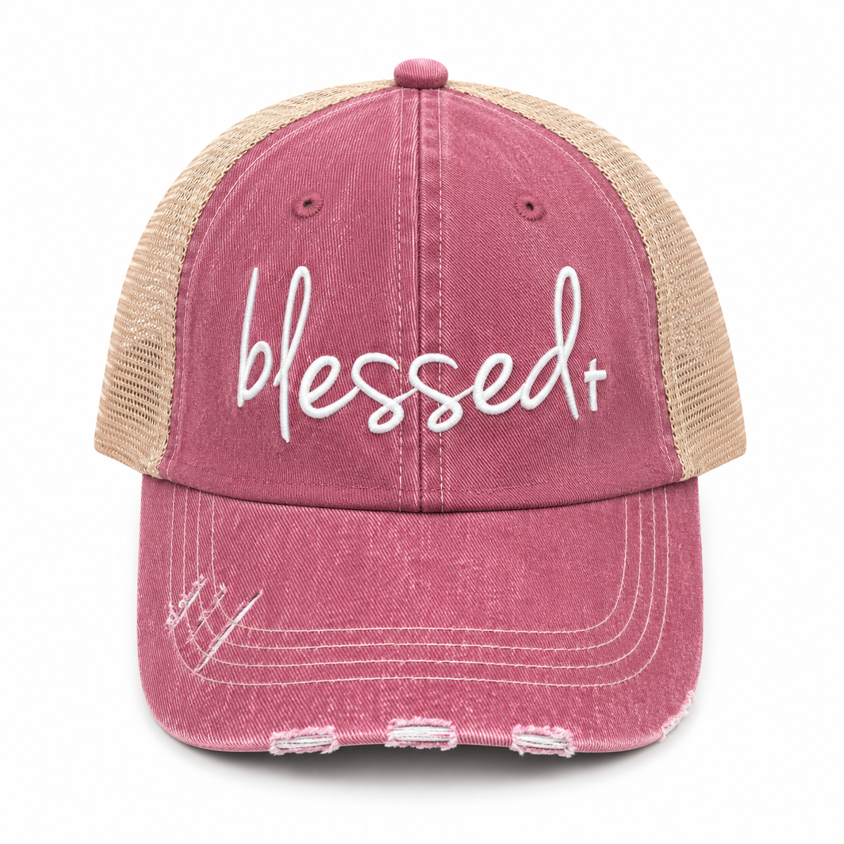 A distressed trucker-style baseball cap with a washed rose pink front panel and brim, tan mesh back panels, and white embroidered text reading 'blessed+' on the front, shown against a plain white background.