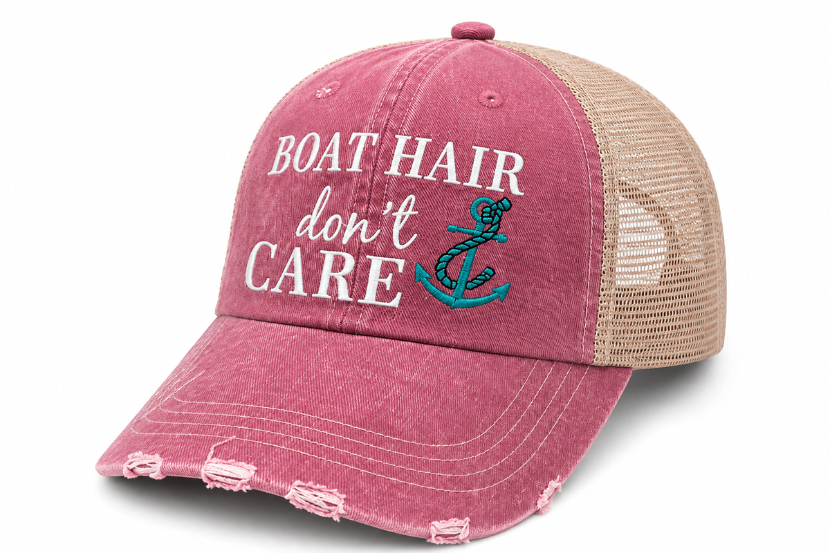 Distressed pink trucker hat with white and teal embroidered "Boat Hair Don't Care" text and anchor graphic, beige mesh back
