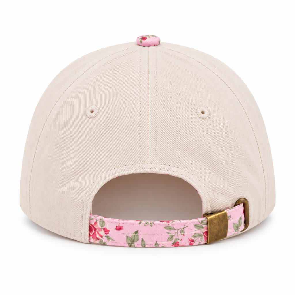 Back view of Walking By Faith Tripping Constantly Baseball Cap in Floral showing cream cotton back panels with two ventilation eyelets, pink floral top button, and pink floral adjustable back strap with antique brass slide buckle closure on white background
