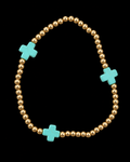 Gold ball bead stretch bracelet with three evenly spaced turquoise cross accents displayed flat in a circle on black background
