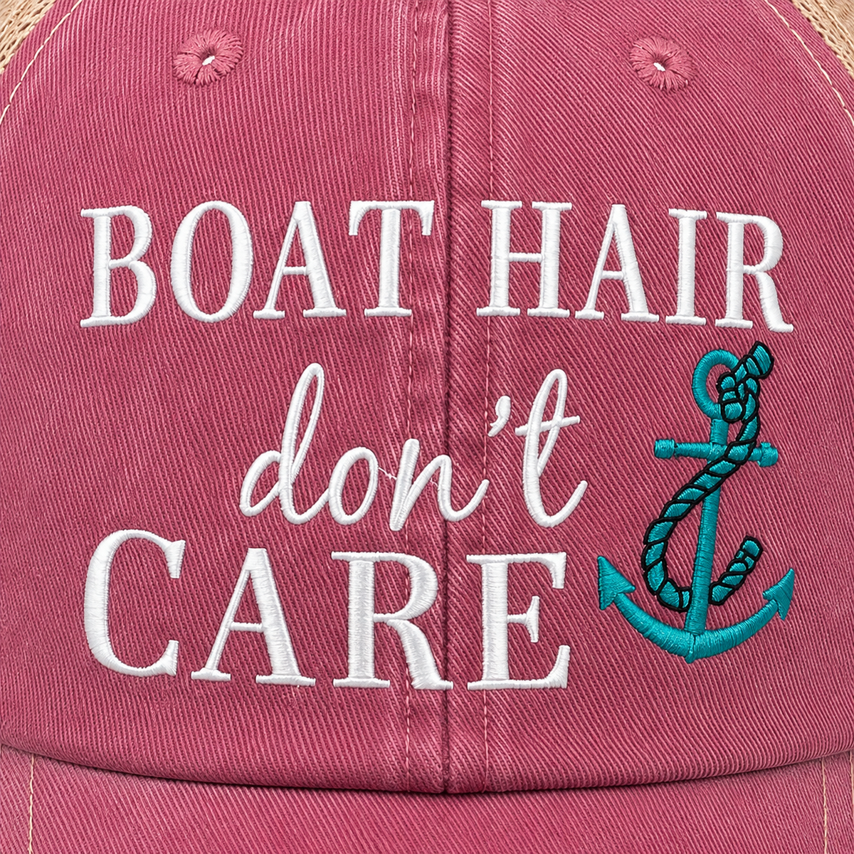 Close-up of embroidered "Boat Hair Don't Care" text with teal rope anchor on distressed pink hat front panel
