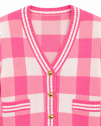 Close-up of Pink Plaid Gold Button Knit Cardigan showing V-neckline with striped knit trim, antique gold dome buttons along button placket, and striped patch pocket trim on pink and white plaid knit on white background
