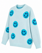Angled front view of the light blue happy face sweater showing textured turquoise smileys, dropped shoulders, and long sleeves
