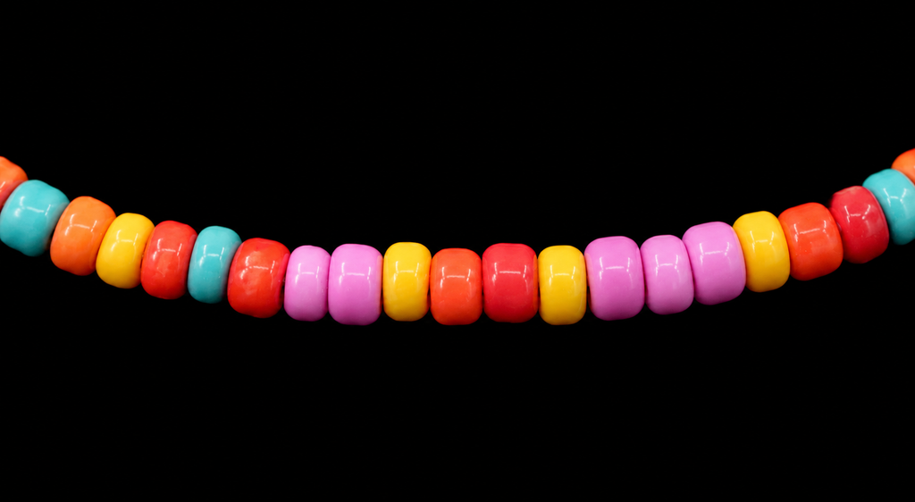 Close-up of bright multicolor seed beads in red, orange, yellow, pink, and turquoise on stretch bracelet
