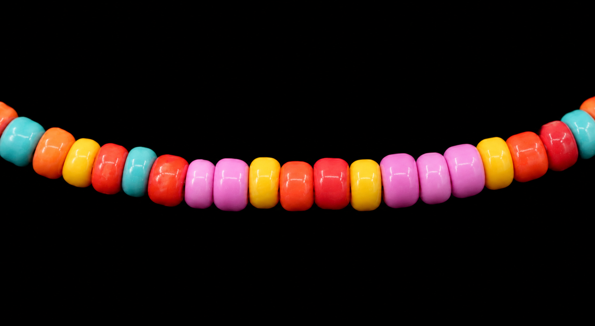 Close-up of bright multicolor seed beads in red, orange, yellow, pink, and turquoise on stretch bracelet
