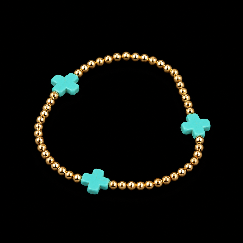 Gold ball bead stretch bracelet with turquoise cross accents shown at an angle on black reflective surface
