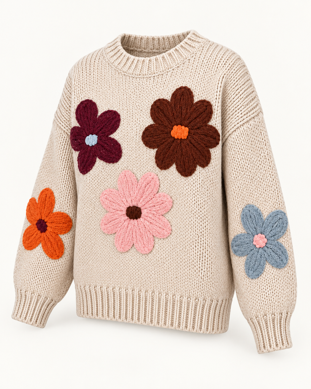 Angled view of the tan floral knit sweater showing colorful stitched flowers across the front and sleeves, dropped shoulders, and ribbed trim
