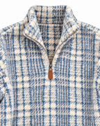 Close-up of the blue and cream plaid fleece pullover showing its stand collar, quarter zipper, brown pull tab, and textured fabric
