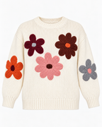 Cream Floral Knit Stitched Sweater front view showing cream ribbed knit with five oversized 3D daisy floral appliqués in burgundy, brown, and pink on the body and orange and gray on the sleeves, ribbed crew collar, and ribbed cuffs and hem on white background
