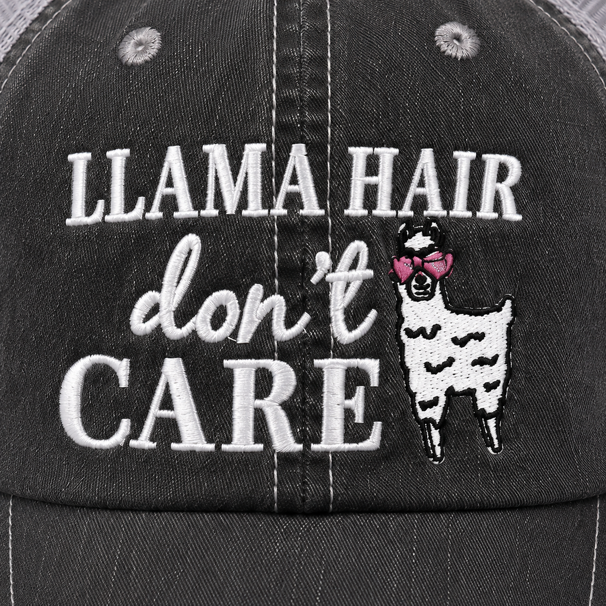 Close-up of Llama Hair Don’t Care trucker hat showing raised white embroidery and llama graphic with pink heart-shaped glasses.