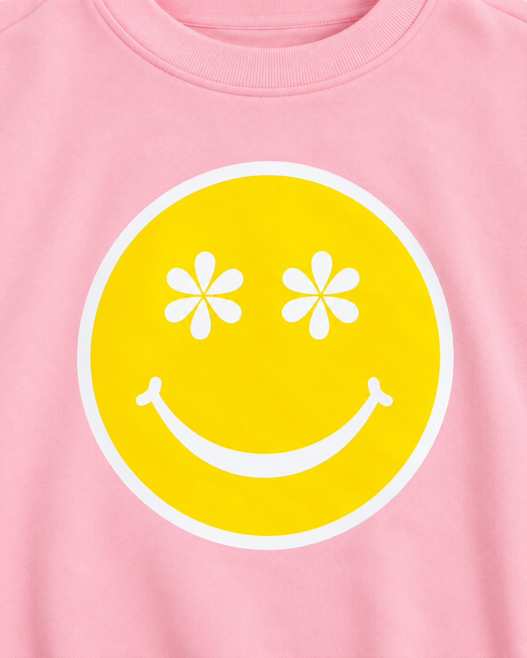 Close-up of the yellow happy face graphic with white daisy-shaped eyes, a white smile, and a white border on pink fabric
