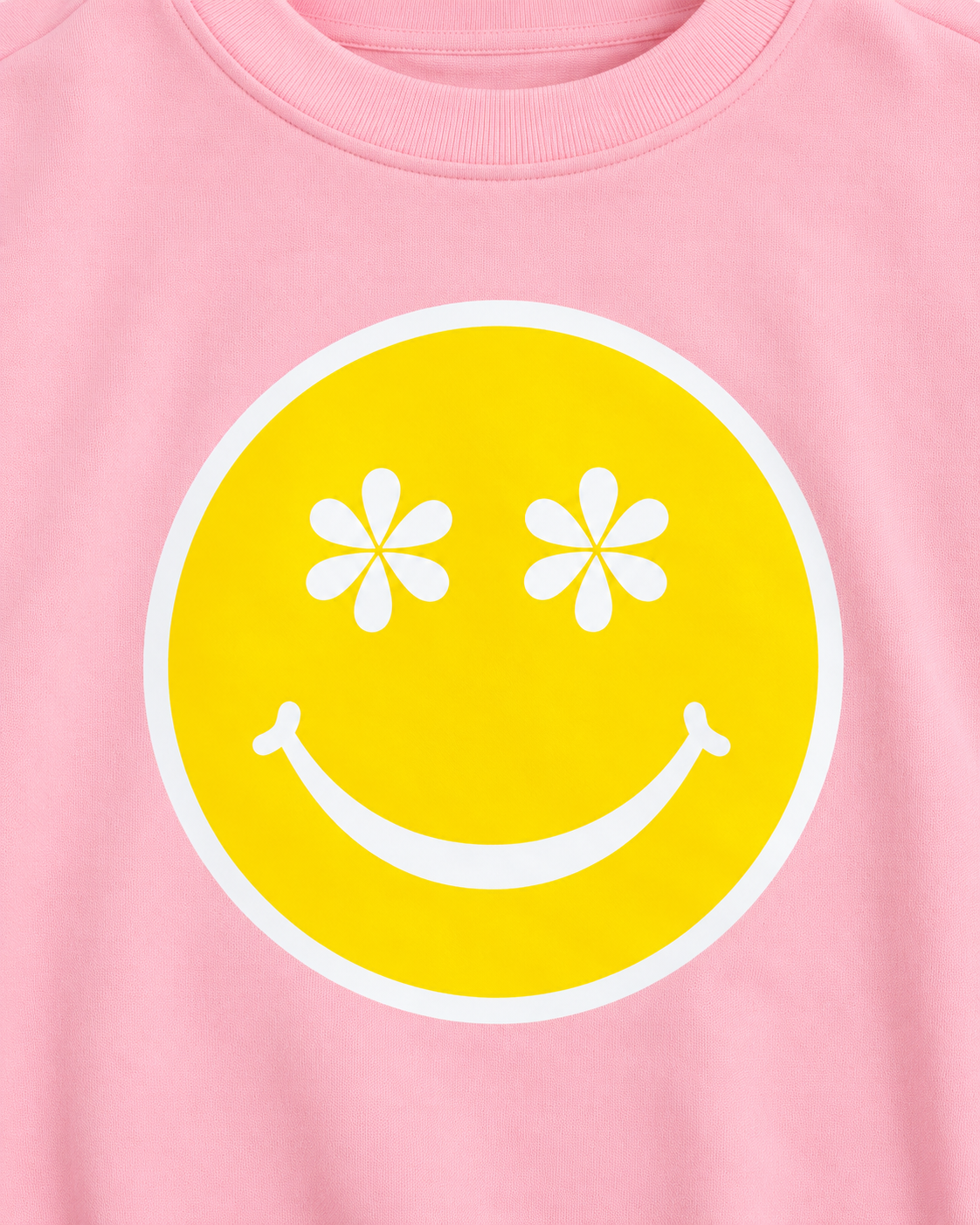 Close-up of the yellow happy face graphic with white daisy-shaped eyes, a white smile, and a white border on pink fabric
