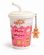 Angled view of the Gingerbread mini wipes cup showing pink holiday illustrations, a white lid, and a dangling gingerbread man charm
