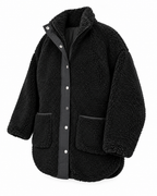 Angled front view of the black sherpa jacket showing its snap-and-zip closure, large front pockets, and curved high-low hem
