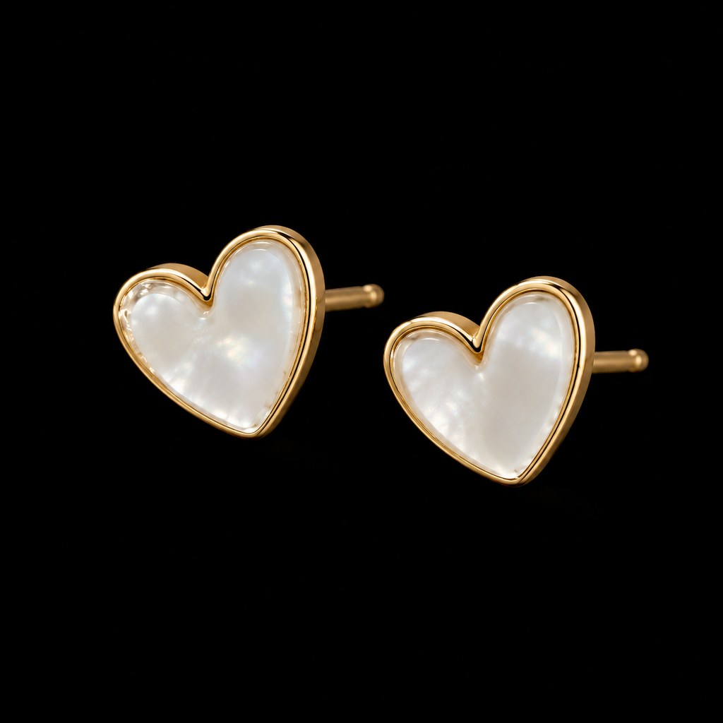 Pearl heart stud earrings with gold-tone trim shown at an angle with gold post backings visible on black background
