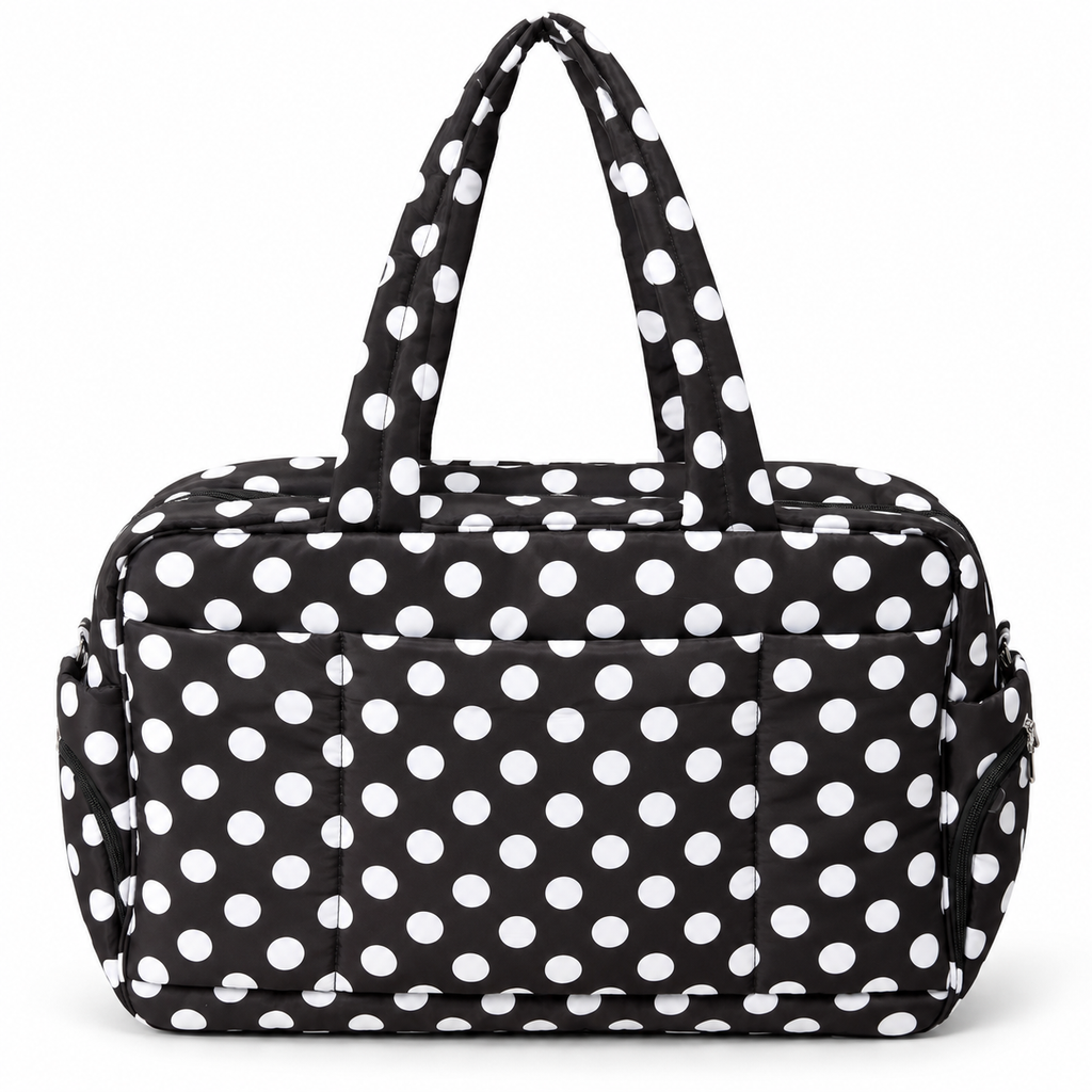Black Polka Dot Shoulder Tote Bag front view showing black padded fabric with bold white polka dots, dual shoulder handles with matching dot print, large front slip pocket, and silver zippered side pockets on white background
