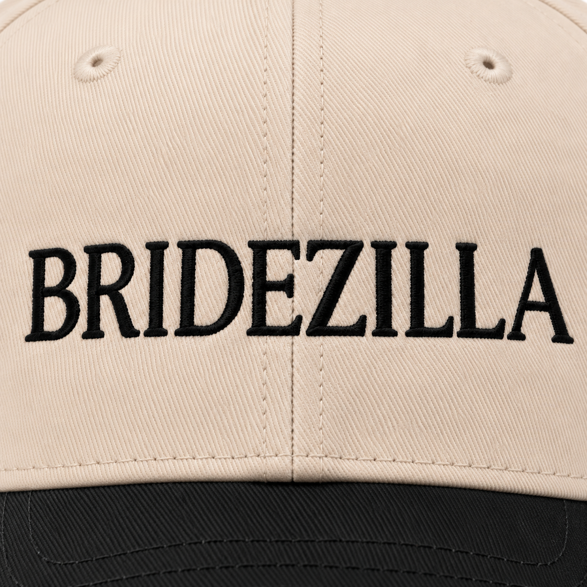 Close-up of bold black embroidered BRIDEZILLA lettering on cream structured front panel of baseball cap
