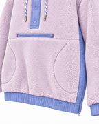 Close-up of the light purple sherpa hoodie showing the front zipper, curved hand-pocket openings, and periwinkle blue side panel and hem
