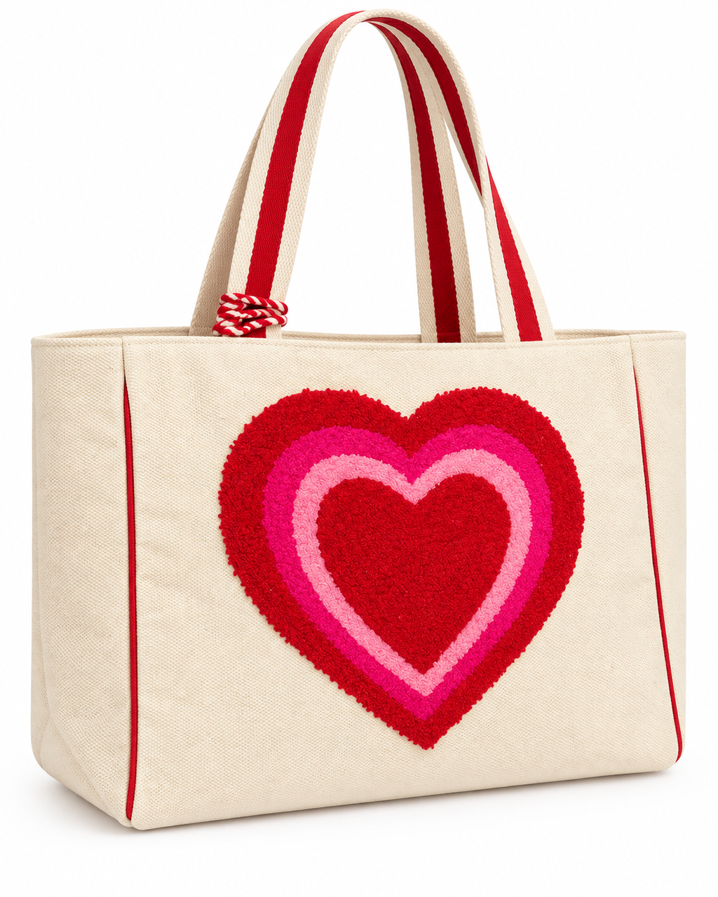 Layered Heart Tote Bag three-quarter angle view showing natural canvas body, large textured punch needle layered heart in red hot pink and light pink, red striped handles, red trim accents, and red rope tassel on white background
