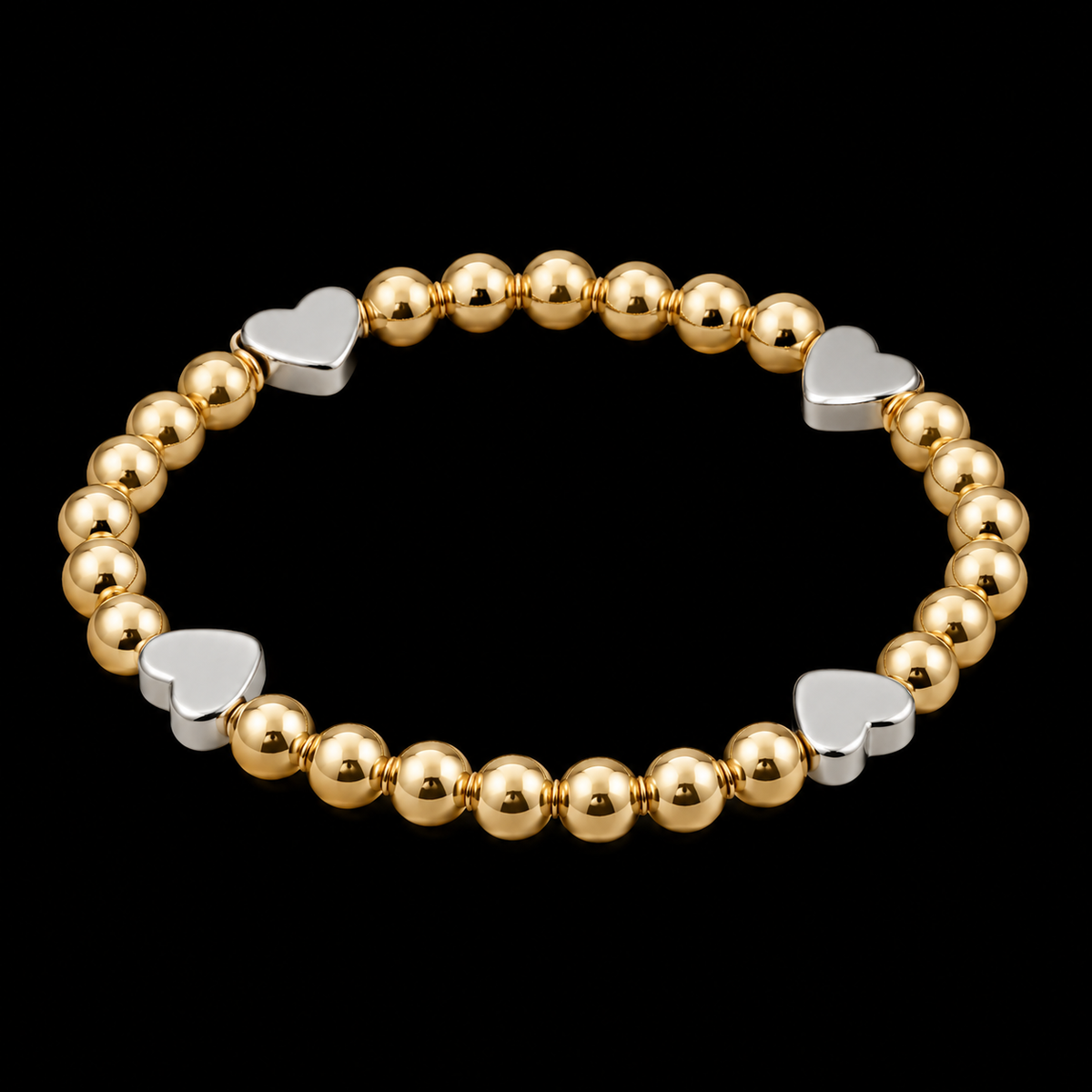 Gold and silver heart beaded bracelet shown at an angle on black background highlighting mixed-metal design
