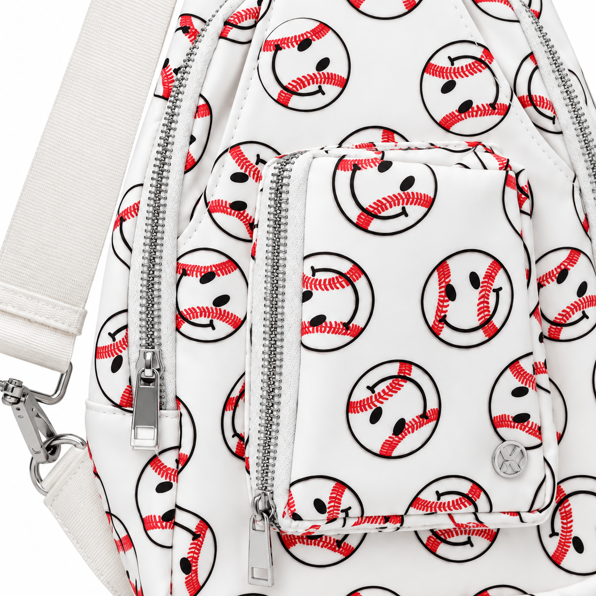 Close-up of Baseball Smiley Sling Bag showing all-over baseball smiley face print with red stitching detail, two silver chain zipper pulls on front compartments, small front zippered pocket, and silver Katydid logo charm
