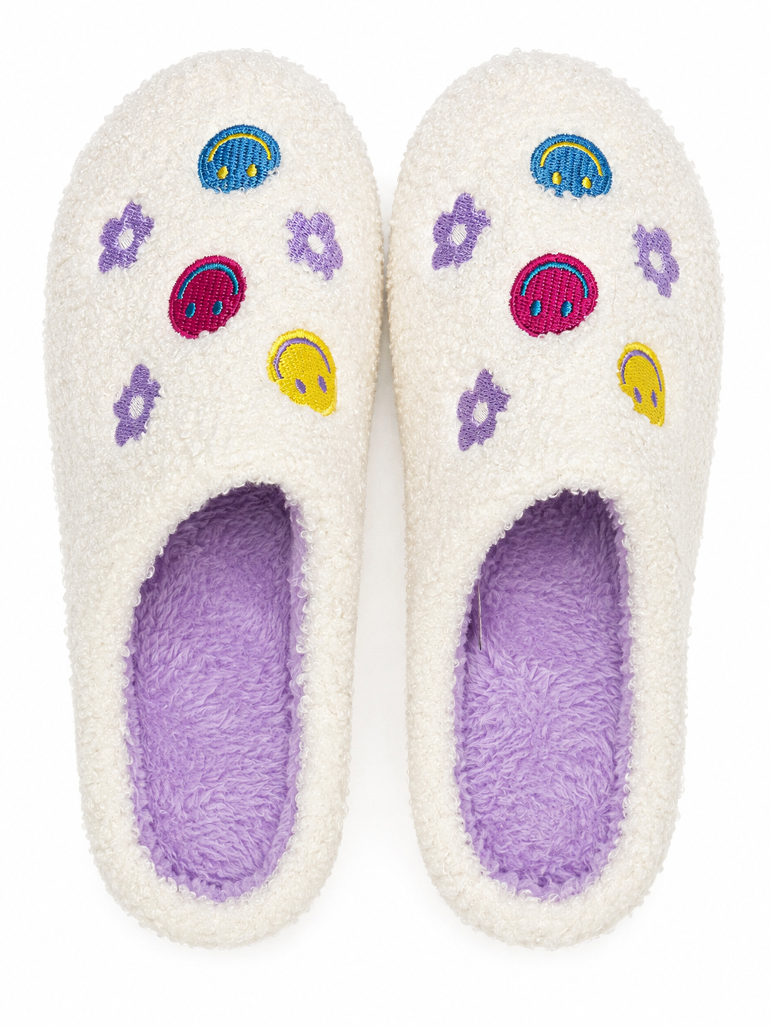 Ivory Smiley Face Fuzzy Slippers flat lay showing colorful embroidered melty smiley faces, purple daisy flowers, and rainbow accents on ivory fuzzy exterior with lavender interior
