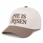 He Is Risen Baseball Cap in Ash Mocha three-quarter angle view showing structured cream cotton crown with mocha decorative script He Is Risen embroidery, curved mocha bill, and mocha top button on white background
