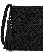 Close-up of Black Woven Bohemian Tassel Crochet Shoulder Bag showing macrame cord diamond lattice and starburst knot detail in solid black, silver zipper pull along top edge, braided cord strap knotted attachment point, and wrapped black suede tassel with cord fringe
