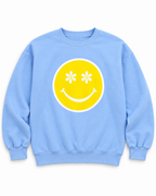 Front view of the light blue sweatshirt with a yellow happy face, white daisy eyes, white smile, and white outline
