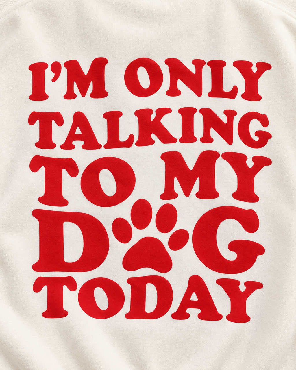 Close-up of the red I'm Only Talking to My Dog Today back graphic with a paw print replacing the O in DOG on cream fabric
