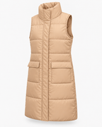 Angled view of the tan long quilted puffer vest showing the sleeveless design, stand collar, covered front placket, and front pockets
