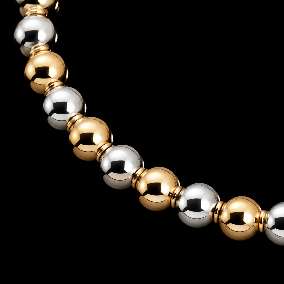 Close-up of alternating polished gold-tone and silver-tone round beads on stretch bracelet
