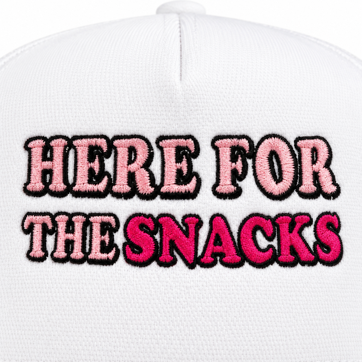Close-up of light pink embroidered Here For The lettering and hot pink embroidered Snacks lettering with bold black outline on white structured trucker hat front panel

