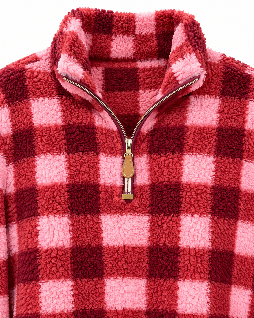 Close-up of the pink and burgundy plaid sherpa pullover showing its stand collar, quarter zipper, tan pull tab, and plush texture
