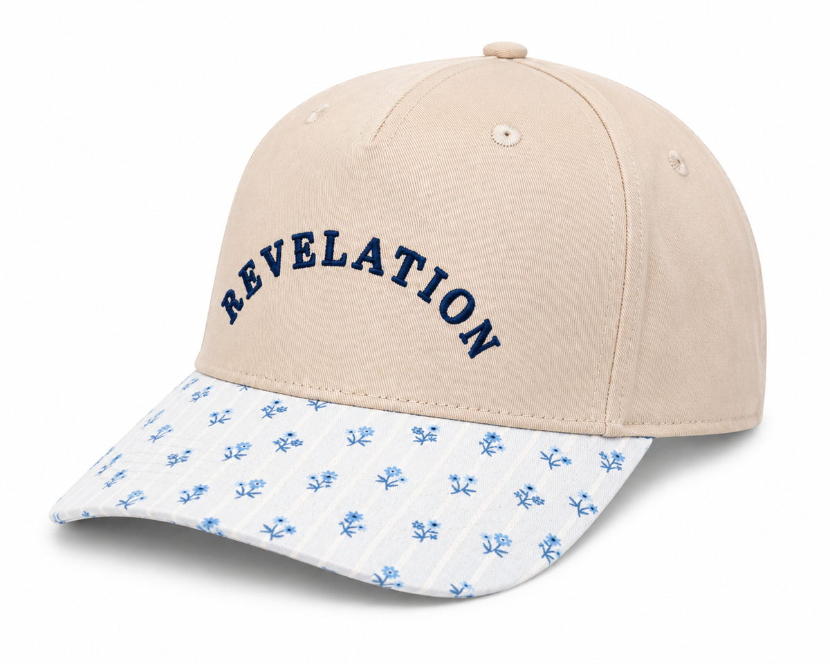 Side view of Revelation Baseball Cap showing sand structured crown, blue floral-print brim, and solid back, on a white background.
