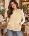 Model wearing a beige quilted vest with ruffled arm openings layered over a white long-sleeve top
