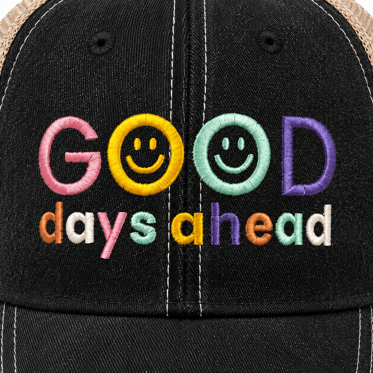 Close up of colorful Good Days Ahead smiley face embroidery on distressed black trucker hat.